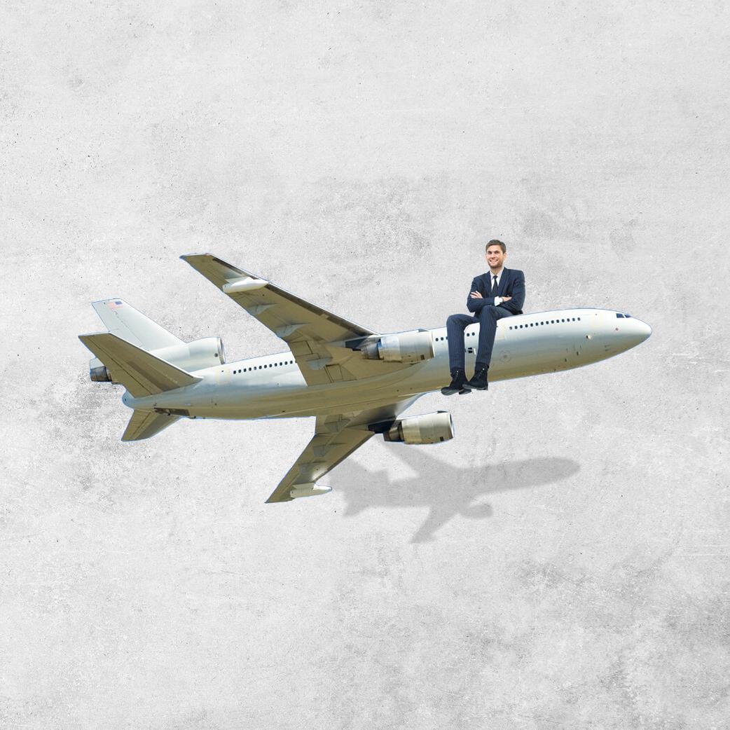 Man in a suit sitting on the nose of a small commercial aeroplane